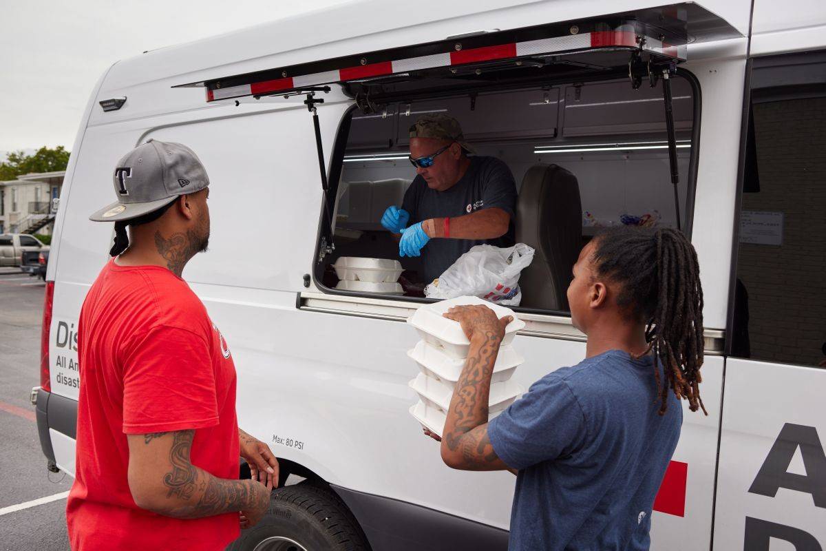A Red Cross volunteer standing in and emergency response vehicle providing meals to people affected by Hurricane Beryl in Texas