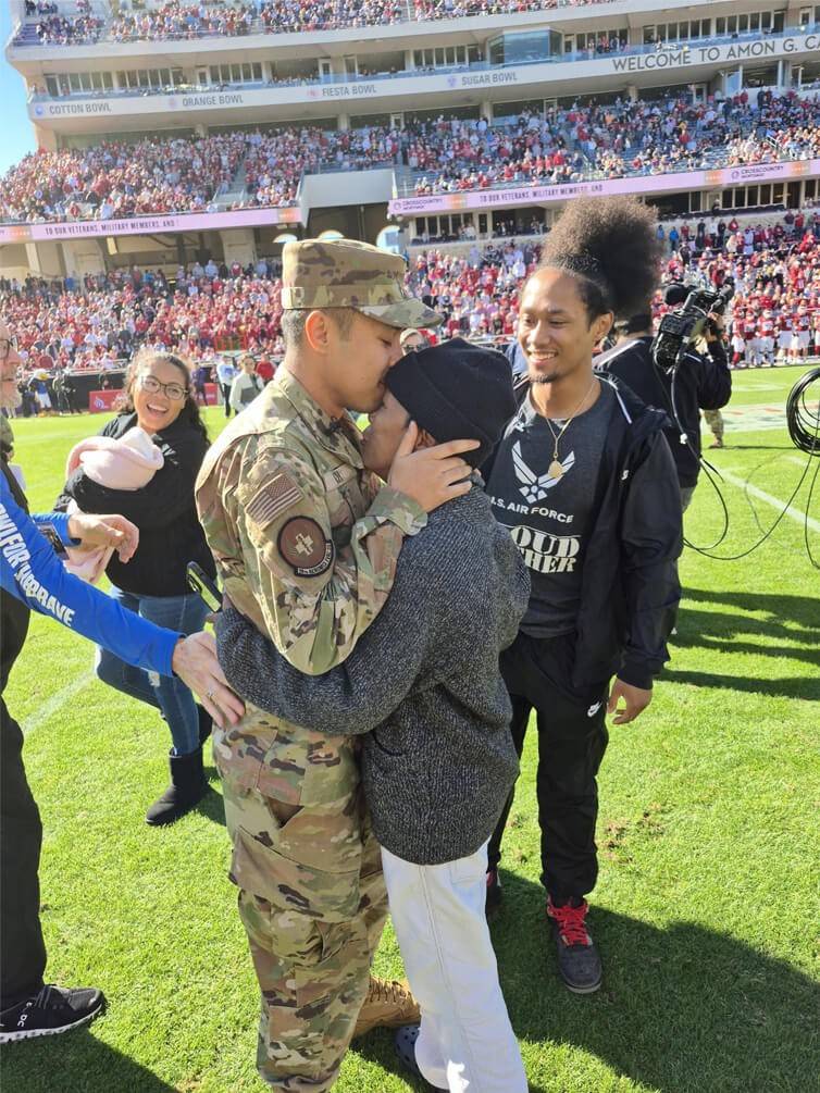 Senior Airman hugs his mother, as his family looks on.