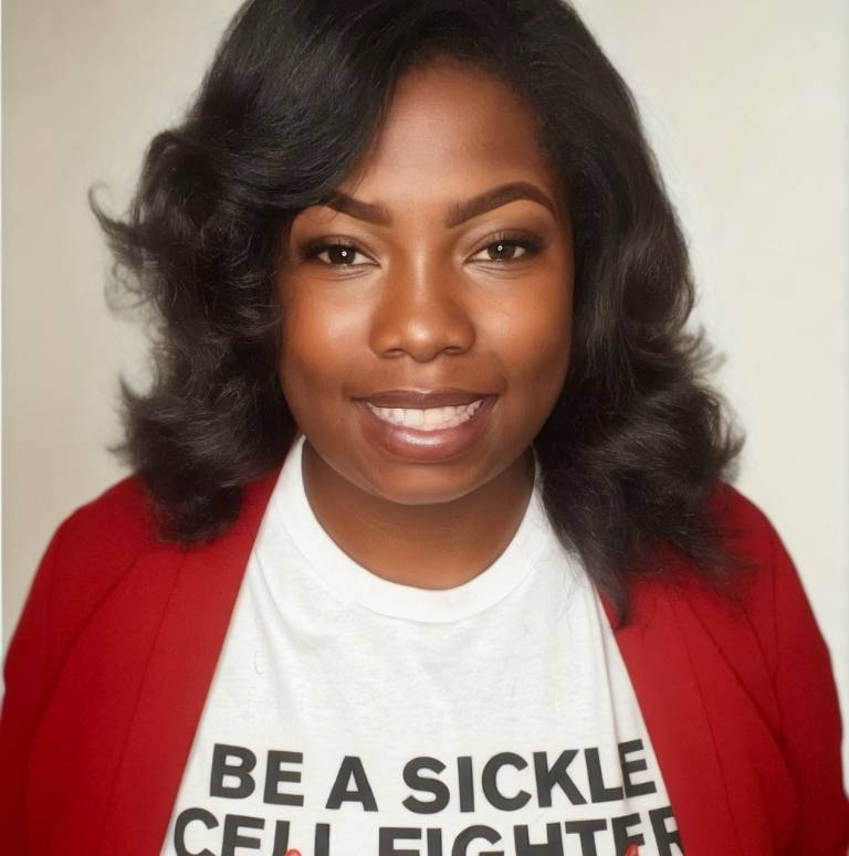 A headshot of a young woman with a red sweater and white tee shirt