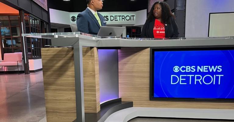 A man and woman sit behind a TV news desk
