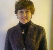 headshot of woman in brown suit with dark turtleneck