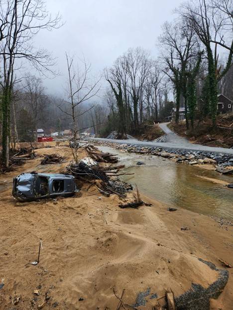 Car over on its side surrounded by flood debris