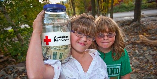 two children smiling holding donation bucket