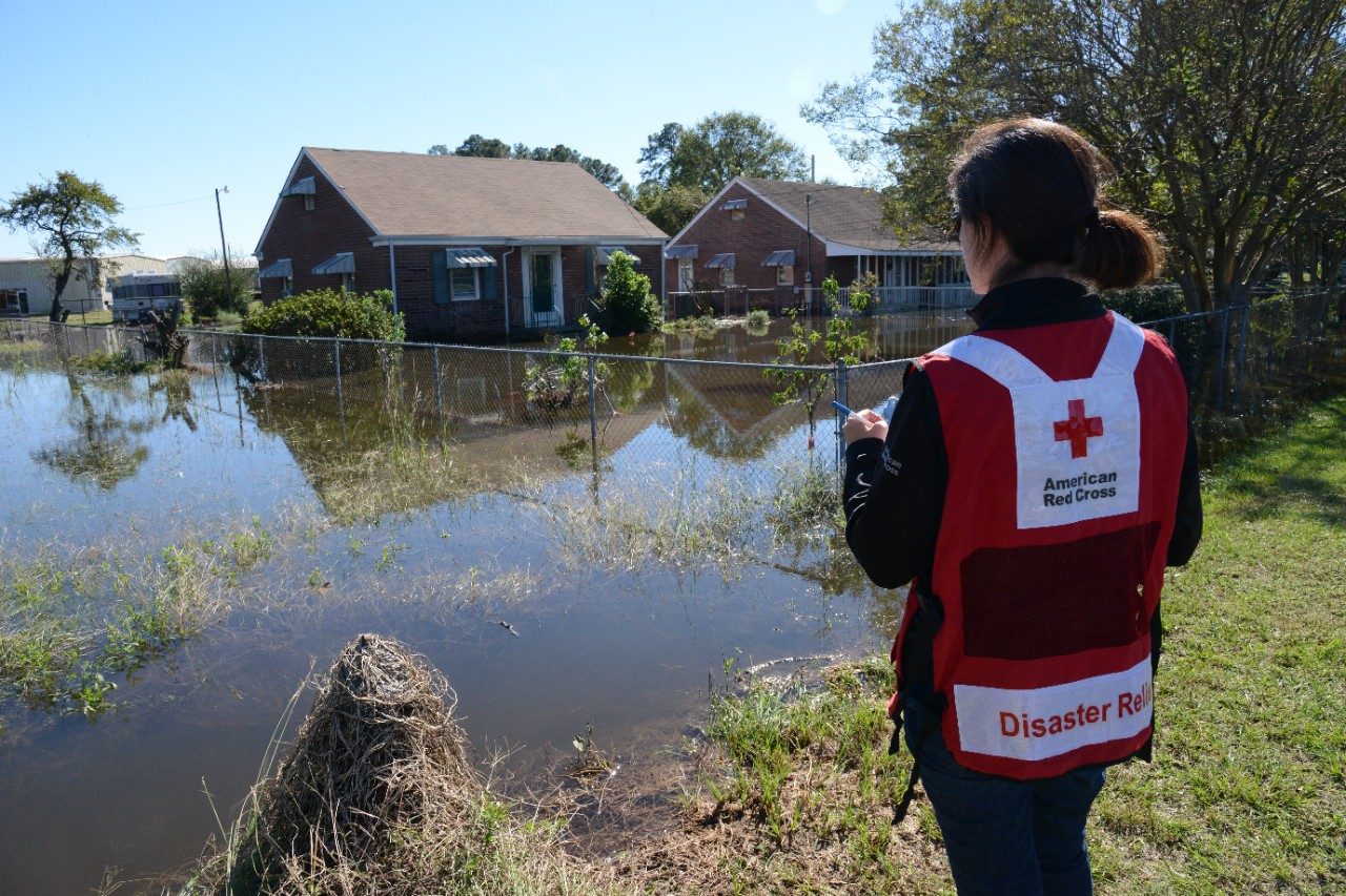 Red Cross volunteer looking at flooded houses.