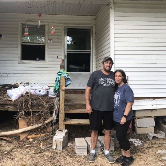 joseph and dana in front of damaged home.