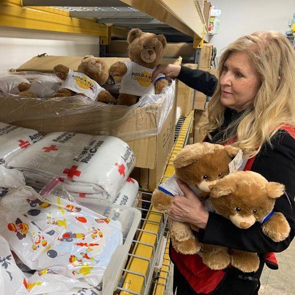 Red Cross volunteer Jane Schumacher holding stuffed teddy bears.