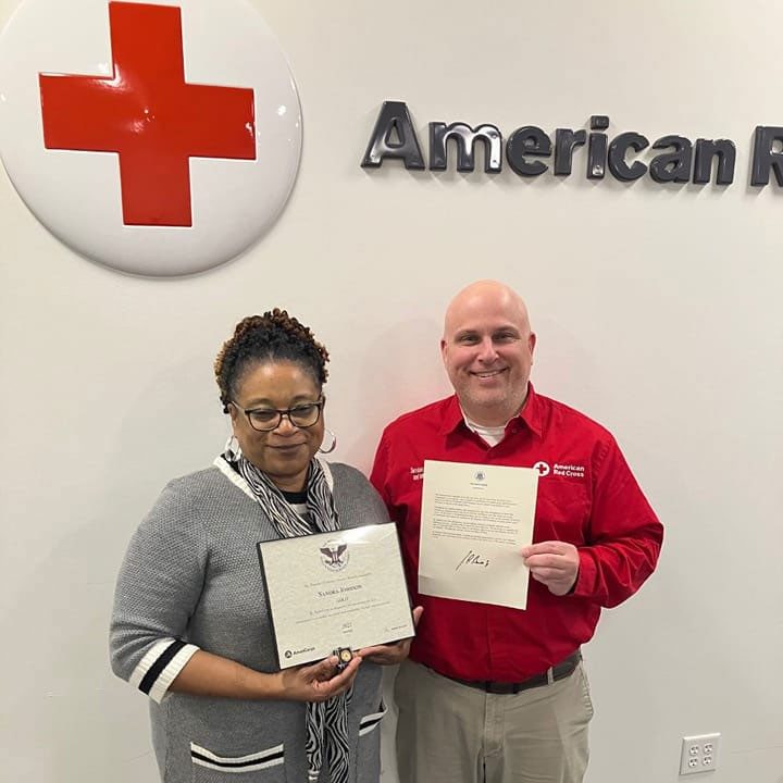 Sandra Johnson standing next to a Red Cross employee and holding the Presidential Volunteer Service Gold Award.