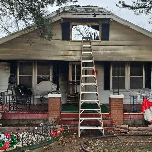 Ladder leaning on attic window on a burnt house.