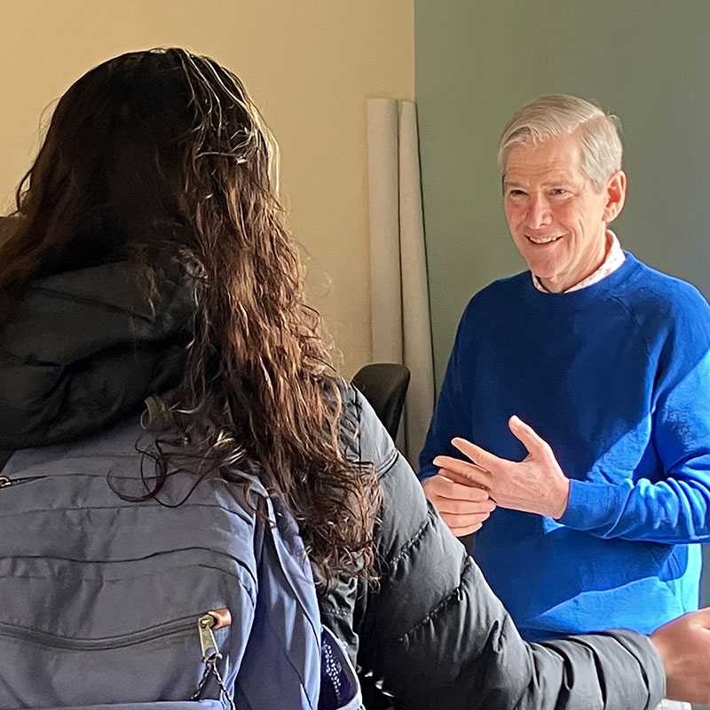 Craig Smith speaking with a young adult wearing a back pack.