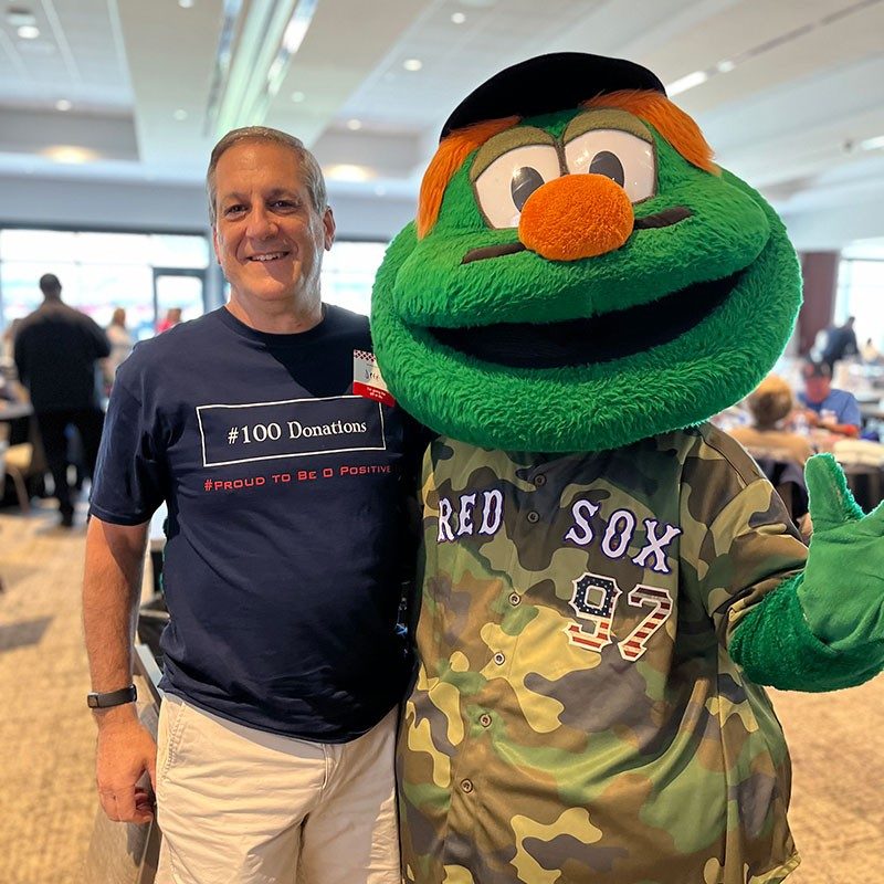 Jeffrey Sack standing next to Red Sox mascot and smiling for picture.