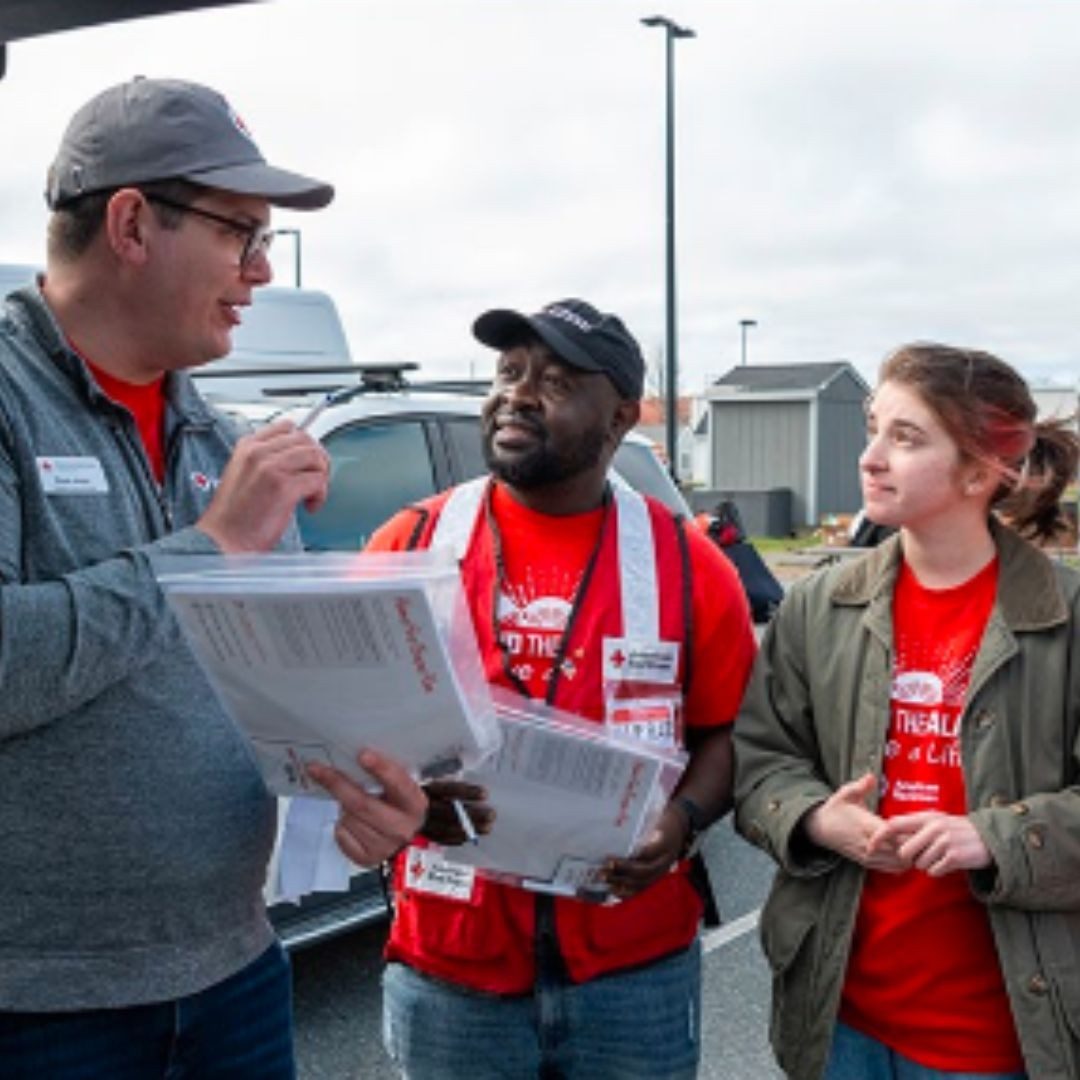 Four Red Cross volunteers in a parking lot going over plans to install smoke alarms.