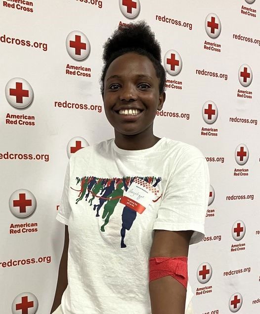 Angelique shows red bandage around arm and smiles for picture.
