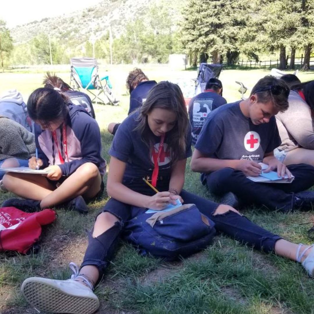youth volunteers writing while sitting in grass