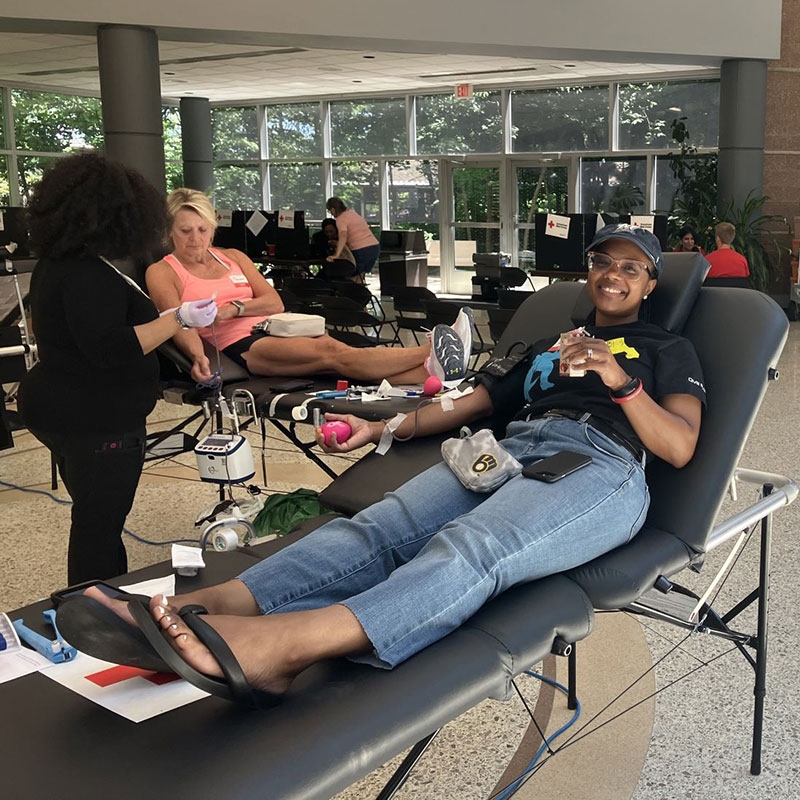 Blood donors sitting on cots and donating blood.