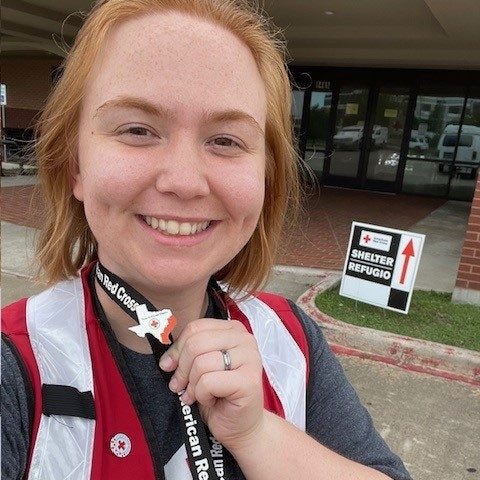 Red Cross volunteer taking a selfie and showing Texas shaped pin that's on a lanyard