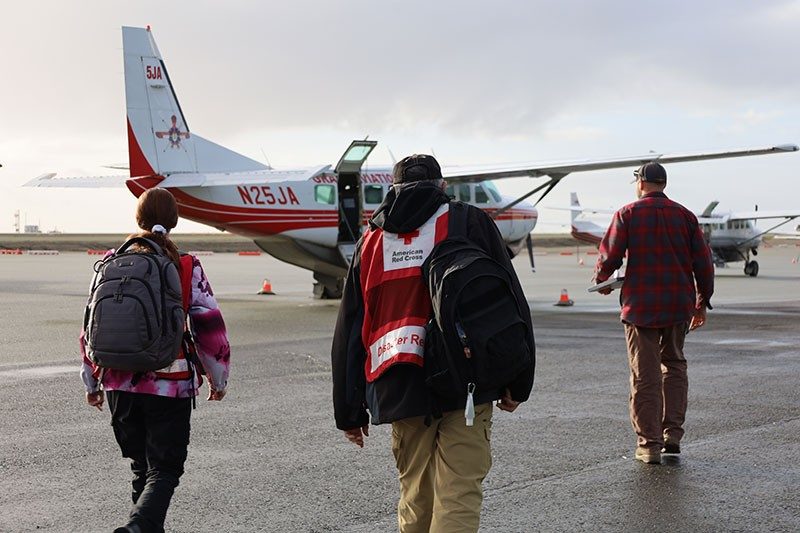 American Red Cross volunteers walking towards a plane to board it.