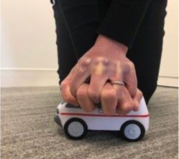 hand covering red cross toy vehicle