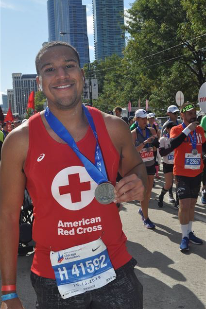 Man in Red Cross shirt holding marathon medal