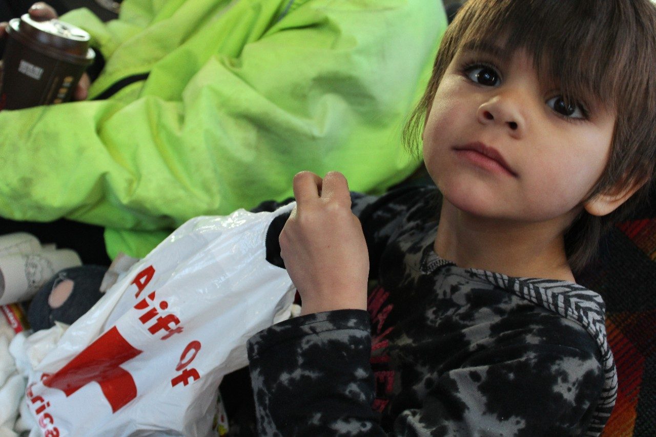 Child holding plastic bag looking