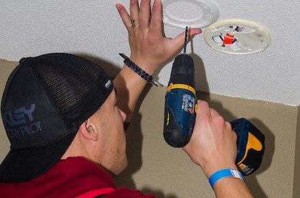 Red Cross volunteer installing smoke alarm in home.