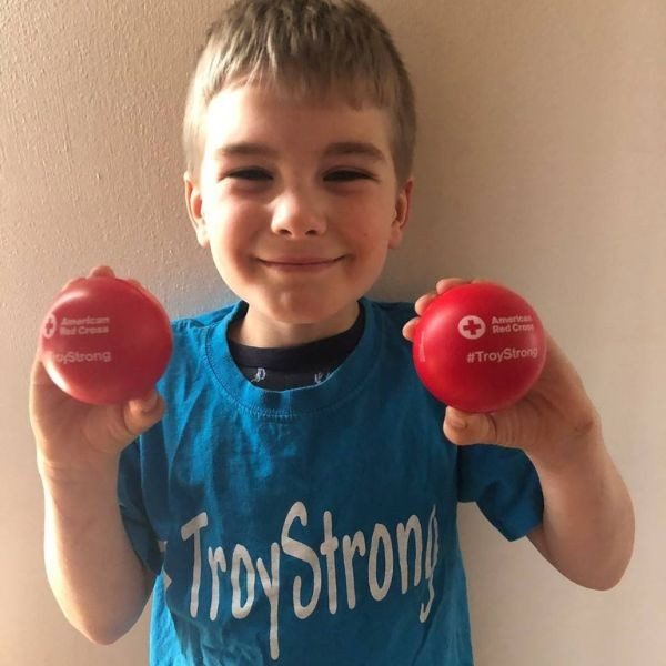 troy smiling holding two red cross balls.