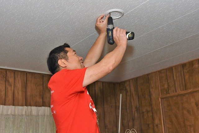 Red Cross volunteer installing smoke alarm on ceiling.