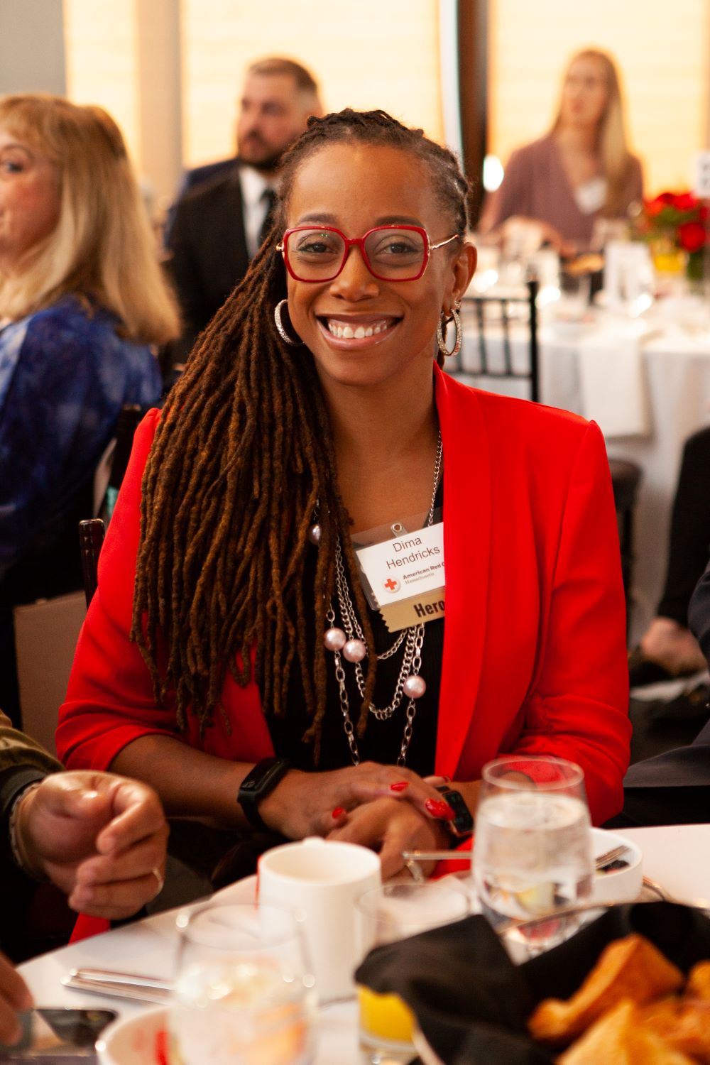 Dima Hendricks wearing glasses and sitting at table at the annual Boston Heroes Breakfast celebration.