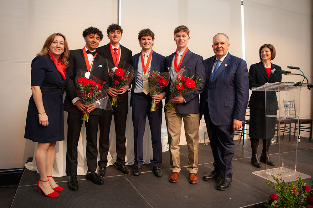 Group photo of the Emergency Professionals wearing their medals and holding bouquet of flowers