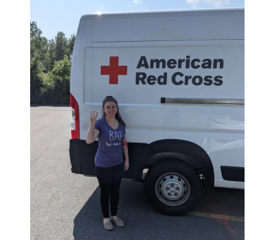 Briana Andella standing next ti Red Cross van in a parking lot.
