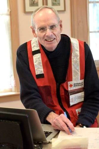 Red Cross volunteer wearing glasses and Red Cross vest.