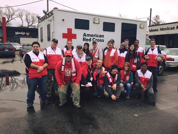 Group pic of Red Cross volunteers next to a Red Cross vehicle.