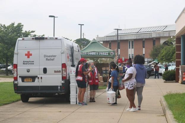 Red cross volunteers and people around a Red Cross disaster relief vehicle.