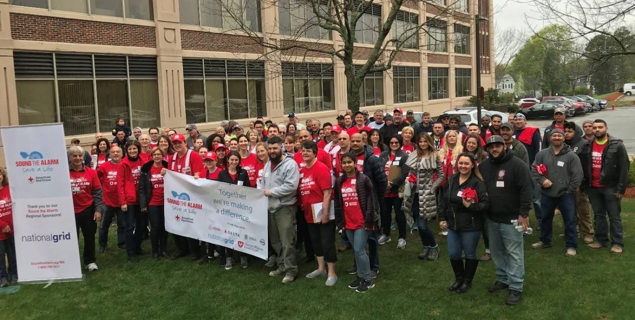 Large group of Red Cross volunteers standing on lawn and holding Sound the Alarm banners.