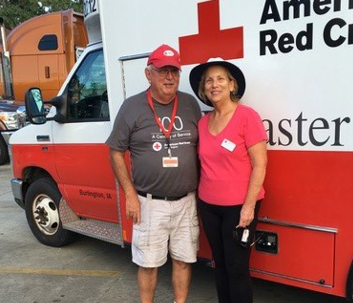 Two Red Cross volunteers standing next to a Disaster Relief Vehicle.