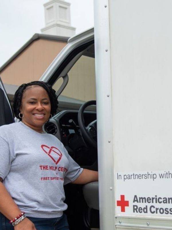 help center volunteer smiling in front of red cross erv