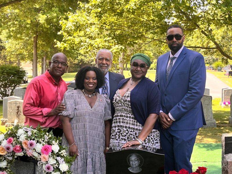 Mary Louise Powell family standing behind her headstone.
