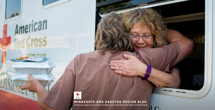 Volunteer in Red Cross food truck hugging a customer.