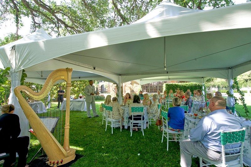 Large canopy with a harp and guests sitting at set tables.