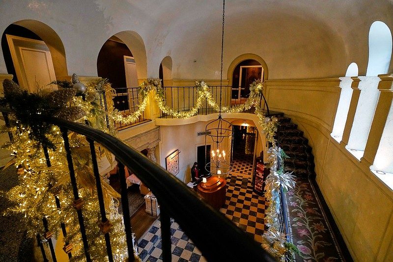 Looking down at reception area from stairs on second story with holiday decorations going across stair railing.