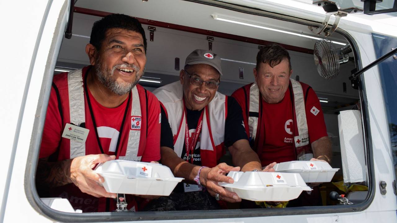three volunteers handing our food trays