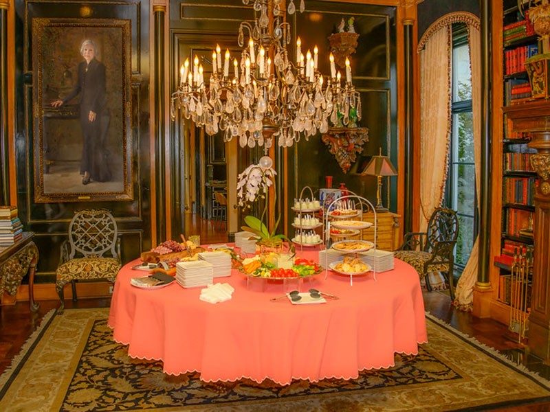 Large round table filled with hors d'oeuvres and a large chandelier above the table.