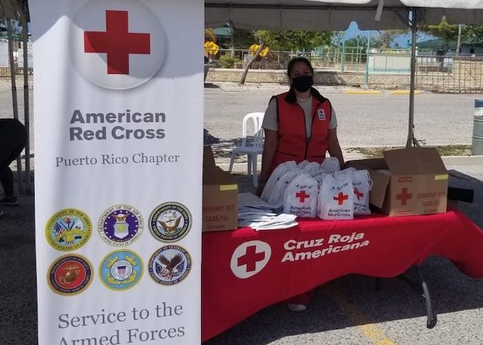 Voluntaria de la Cruz Roja Americana atiende una mesa informativa sobre los Servicios a las Fuerzas Armadas.