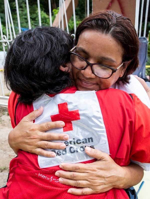 Voluntaria da un abrazo reconfortante a señora afectada por un desastre.