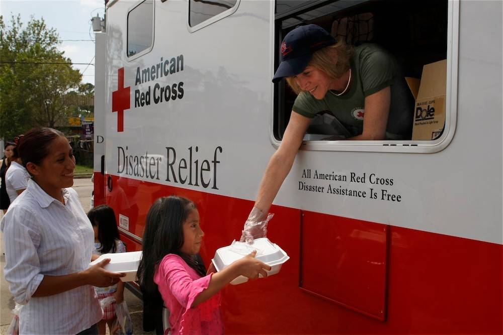 Red Cross President and CEO Gail McGovern chats with Gabriella Centero and her mother while serving meals from the Red Cross mobile feeding vehicle. Many neighborhoods in Houston are without power creating the need for feeding operations directly into the affected neighborhoods.