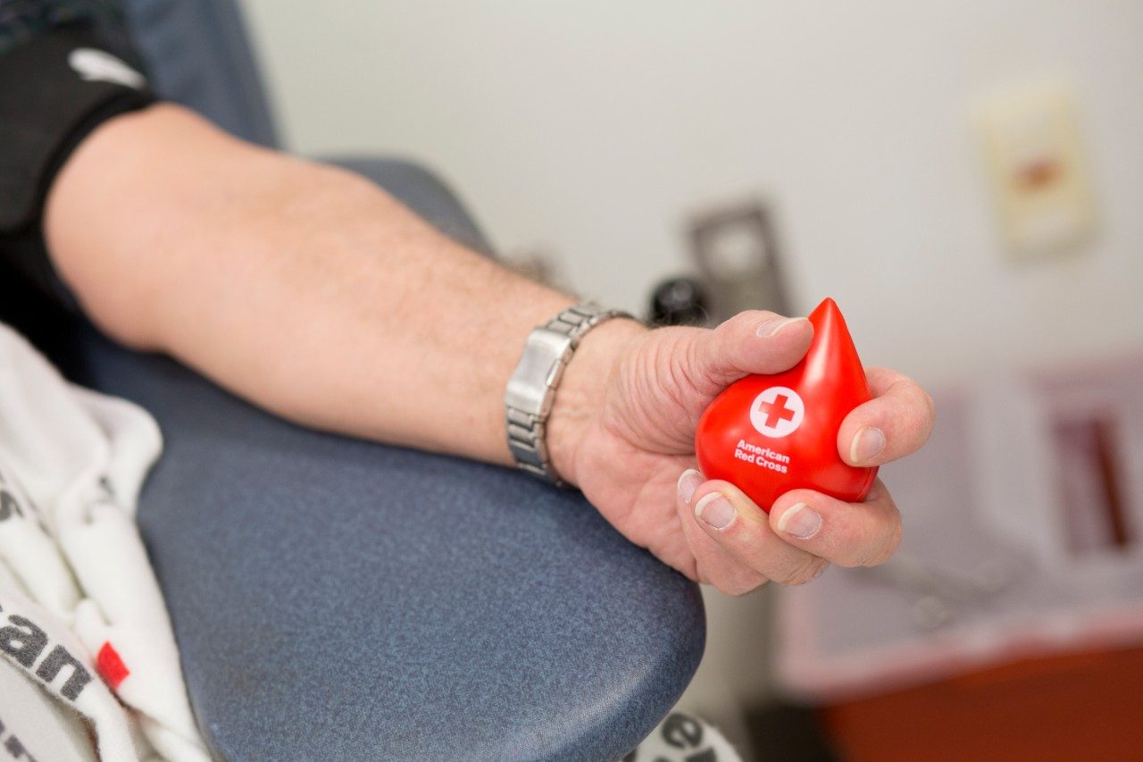 Hand squeezing Red Cross blood drop shaped stress ball.
