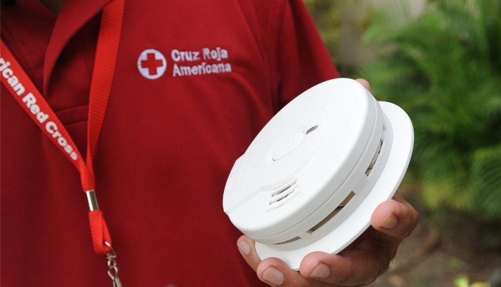 Red Cross volunteer holding a smoke alarm.