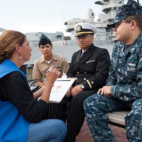 Volunteer having a conversation with three uniformed servicemembers.