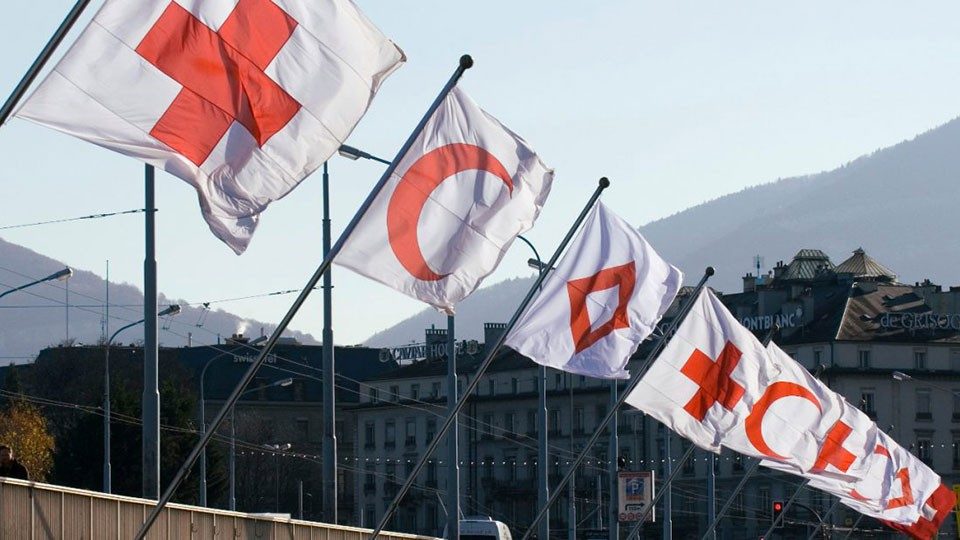 Multiple Red Cross, Red Crescent and Red Crystal flags.