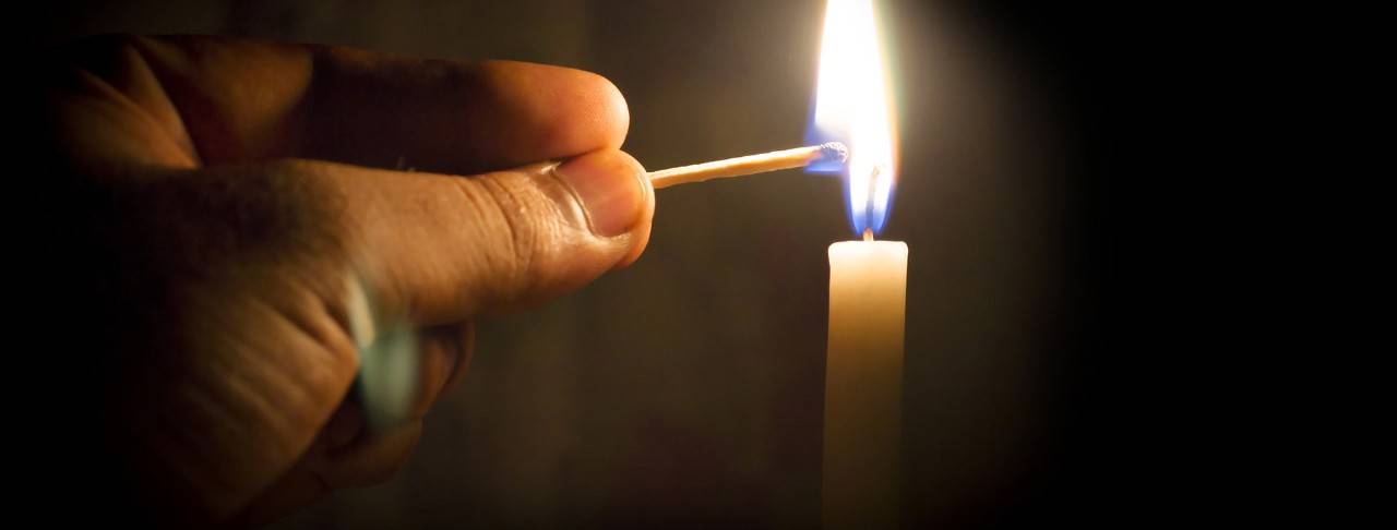 Close-up of a hand lighting a candle